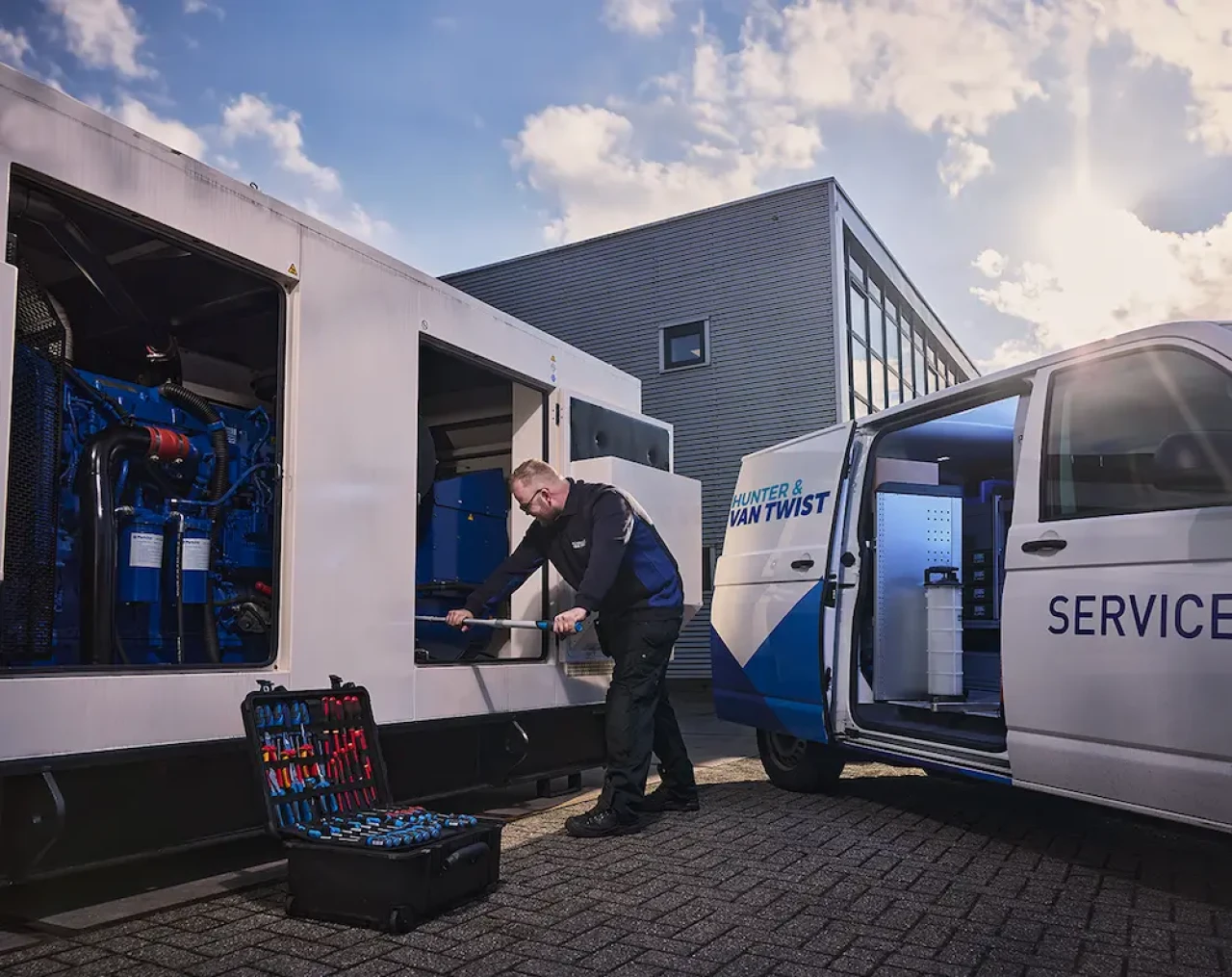 Technicien de service Hunter intervenant sur un groupe électrogène avec un véhicule d'assistance équipé