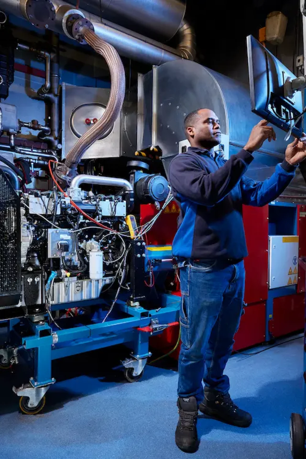 Technicien de service effectuant un test au banc de charge pour la révision d'un moteur industriel