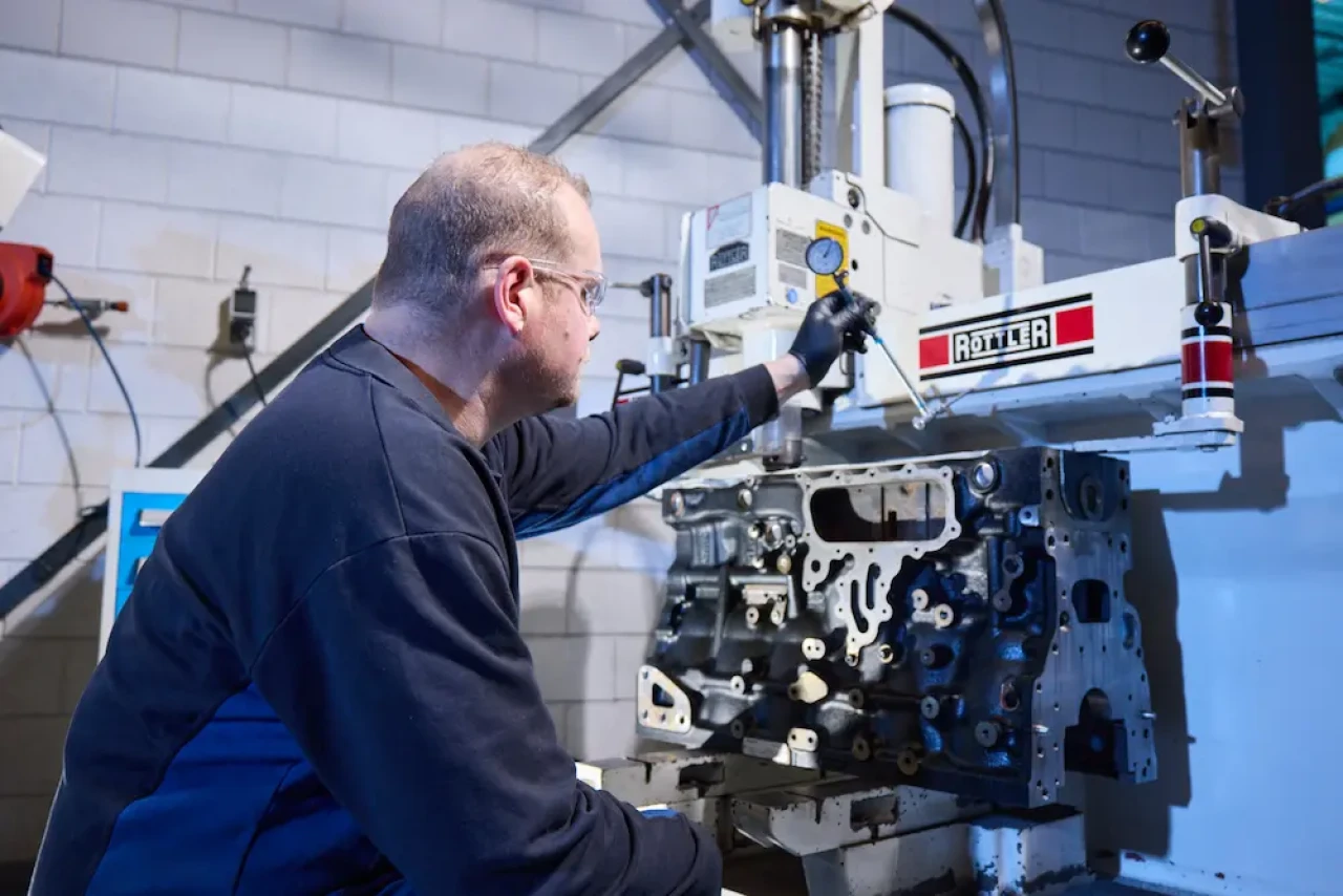 Technicien de service effectuant le honage d'un cylindre lors de la révision d'un moteur industriel